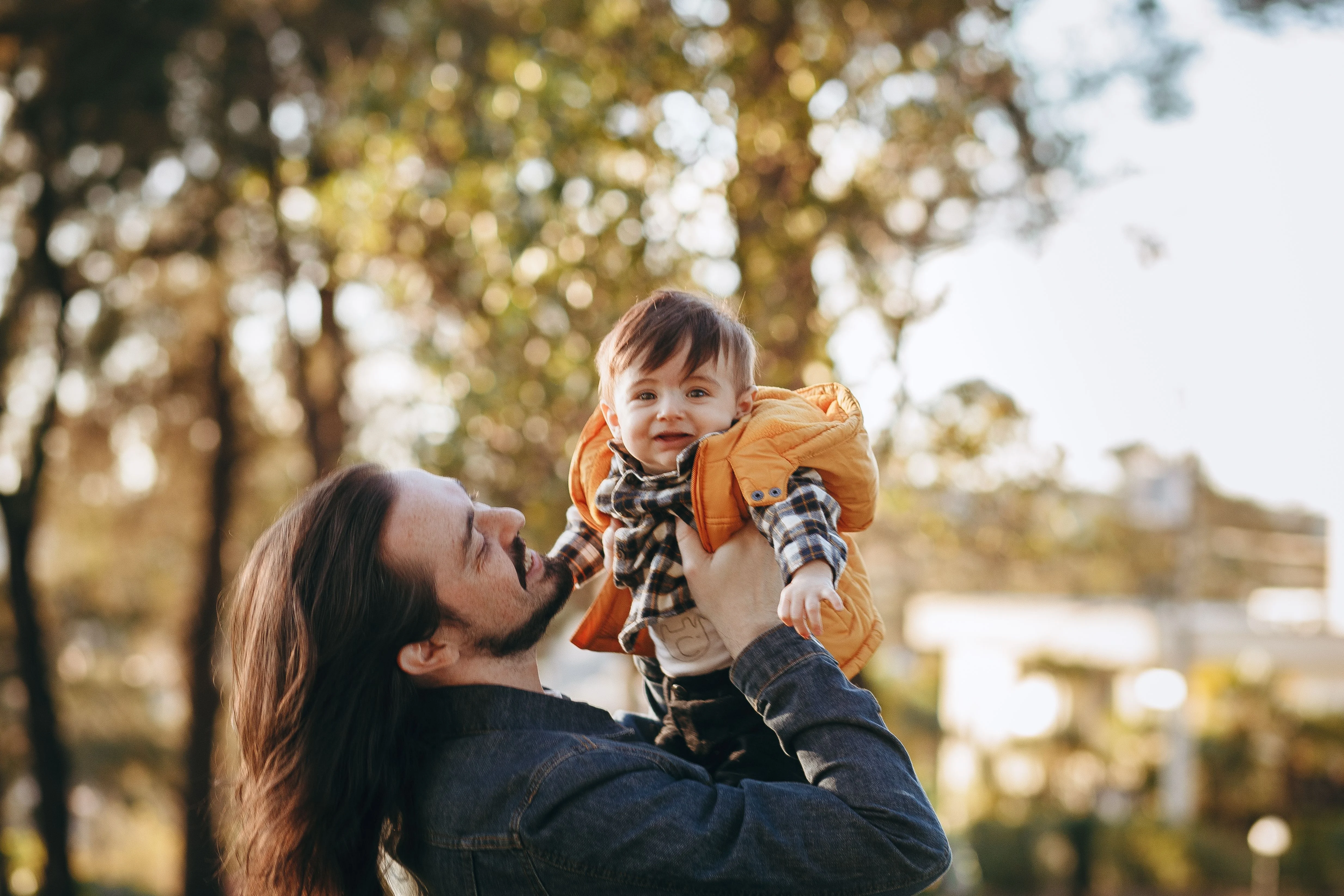 An adult holding a smiling young child outdoors.