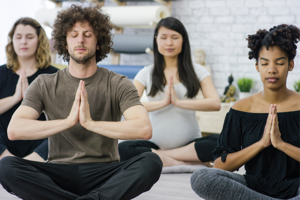 Group of people sitting cross-legged meditating.